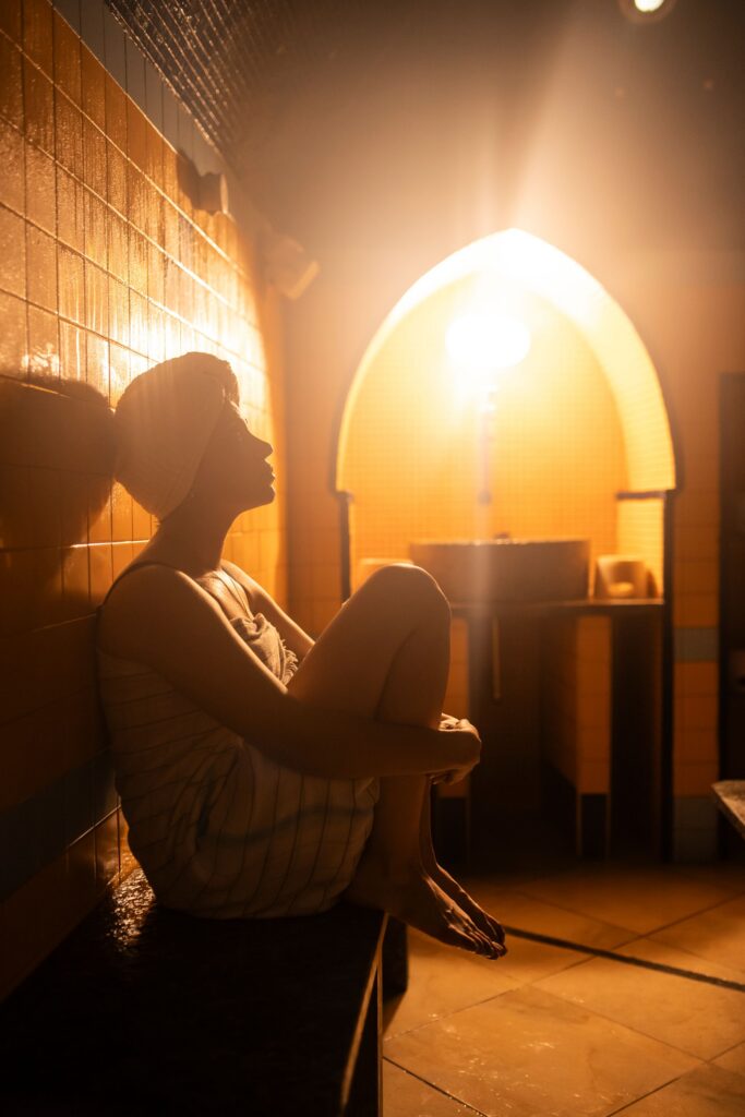 Donna avvolta nel telo che si rilassa nel vapore della sala calda dell'hammam